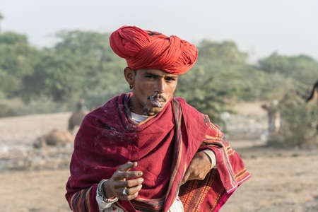 Pushkar, India - Nov 14, 2018: Indian man in the desert Thar during Pushkar Camel Mela near holy city Pushkar, Rajasthan, India. This fair is the largest camel trading fair in the worldのeditorial素材