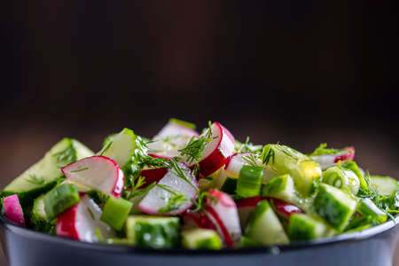 Healthy fresh vegetables salad, close up. Delicious vegetable diet salad of cucumber, radish, green onion, dill and olive oil. Concept healthy meal and mediterranean kitchenの写真素材