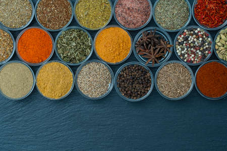 Assortment of aromatic spices, seeds and dry herbs for cooking food on background in small glass bowls, close up, top view, copy spaceの写真素材
