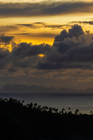 Palm trees silhouette and beautiful sunset over the sea water on the island of Koh Phangan, Thailand. Travel and nature concept. Evening sky, clouds, sun and sea waterの写真素材