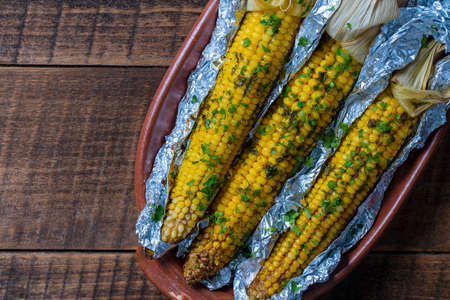 Tasty corn baked in foil with butter, garlic, chili, parsley and sea salt. Grilled corn in aluminum...