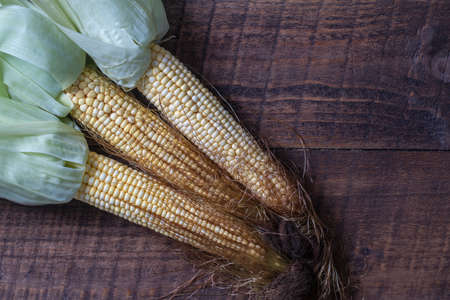 Raw sweet corn on brown wooden table. Top view, close up, copy space. healthy food concept
