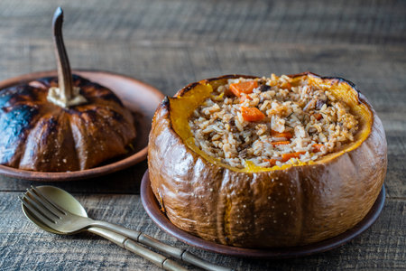Great pumpkin baked with a filling close up. Stuffed roasted orange pumpkin, whole baked, filled with a tasty mixture of rice, raisins and spices on wooden tableの写真素材