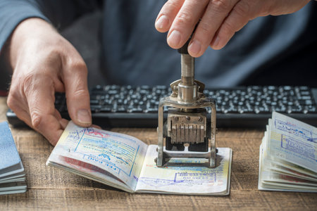 Immigration and passport control at the airport. Man border control officer puts a stamp in the international passport, close up. vacation and travel conceptの写真素材