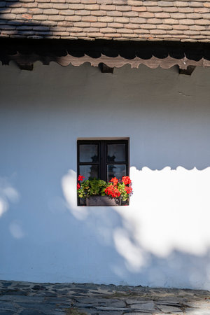 Wooden window in an old farm house with colorful potted flowers in the ethnographic village of Holloko in Hungary, close upの写真素材