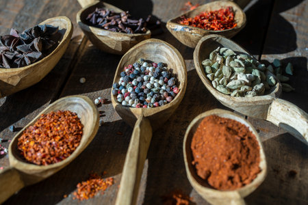 Set of spices in wooden spoons, close up, top view. Various pepper, chili peppers, cardamom, carnation, star anise, paprika, and saffron for cookingの写真素材