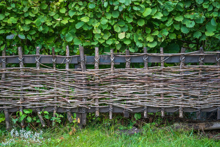 Wicker rustic wooden fence made of sticks in the courtyard in the Alpine village, Austria, close upの写真素材