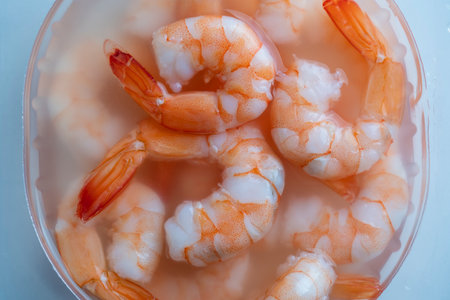 Juicy delicious peeled shrimp in sauce in a transparent plastic box, close-up, top view, preparing a seafood dishの写真素材