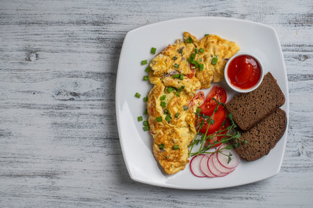 Stuffed omelette with onions, tomato, pepper, eggs and cheese in plate on white wooden background. Healthy diet food for breakfast. Tasty morning food. top view, close up, copy spaceの写真素材
