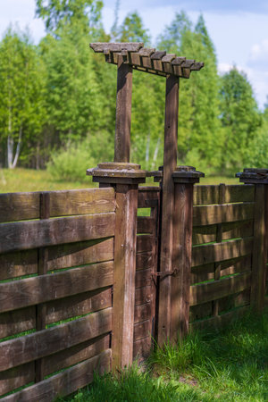 Wooden garden fence with closed door and green grass on a spring day at backyardの写真素材