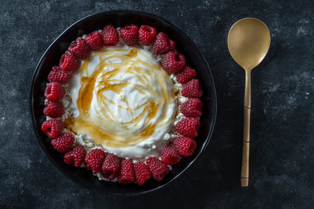 Natural organic yogurt with fresh red raspberries and cottage cheese for breakfast, top view, close up. Delicious morning breakfast on a black backgroundの写真素材
