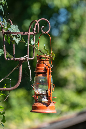 A single old red kerosene lantern hanging against a garden background in the yard in the ethnographic village of Holloko in Hungaryの写真素材