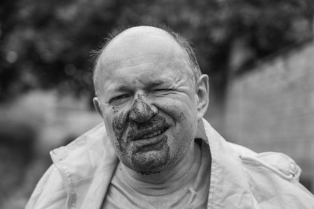 Portrait of a man with a dirty face after falling into a puddle in the rain, close up. black and whiteの写真素材