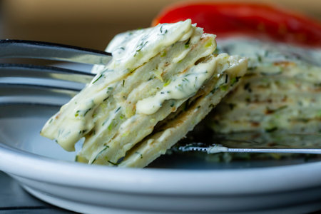 Zucchini savory layered cake with red tomato and green dill in white plate, close up. Pie with zucchini, cheese and herbs on the tableの写真素材
