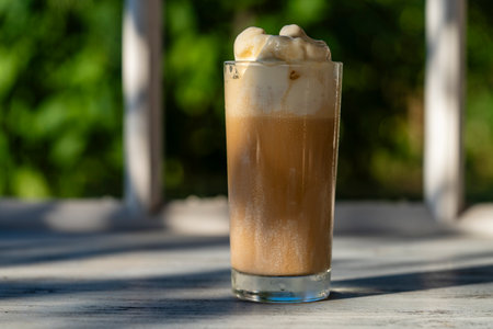 Glass of coffee with ice cream on the windowsill next to the window. Cold summer drink. close upの写真素材