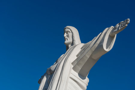 Detail 12-meter-high statue of Jesus Christ is a copy of a similar sculpture in Rio de Janeiro. Truskavets city, West Ukraine. Large statue of Jesus Christ with outstretched arms against the blue skyの写真素材