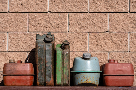 Many old rusty iron fuel cans on a table near the garage, close up. Various metal painted canisters for gasoline, retro styleの写真素材