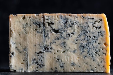Piece of blue cheese on dark background, close up