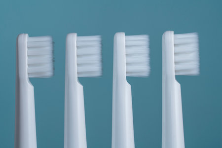 Four white plastic toothbrushes on a blue background, close upの写真素材