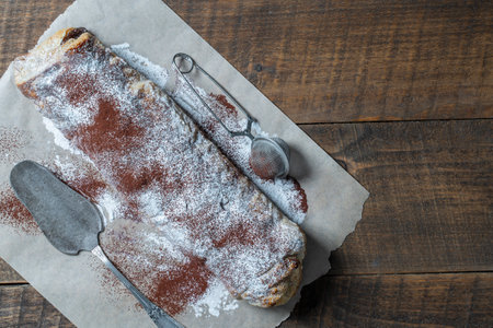 Traditional freshly baked whole apple strudel on wooden table, close up. Fresh homemade pastries with fruit or berry filling, copy space for textの写真素材