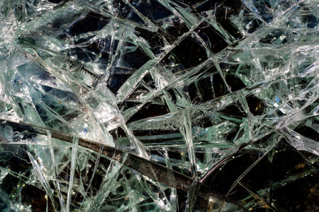 Cracks from a bullet shot in armored glass in combat vehicle. Armor piercing glass of damaged military fighting vehicle during war between Russia and Ukraine. Texture bulletproof glass after an attackの写真素材