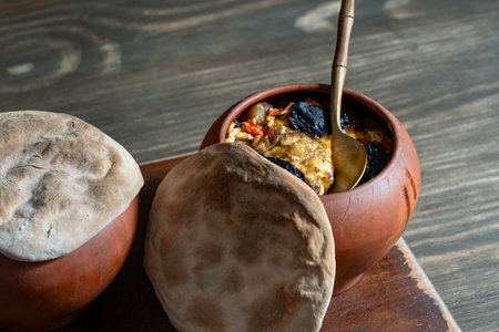 Two clay pots with stewed vegetables on a wooden table, close up. Stewing food in earthenware is considered healthyの写真素材