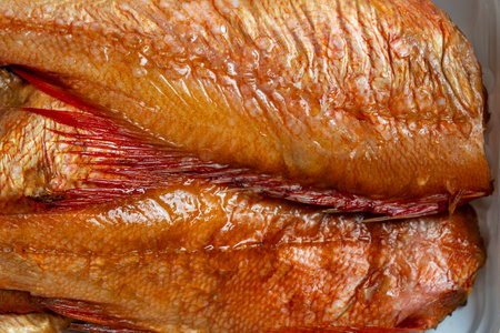 Hot smoked perch fish in white plastic packaging on wooden background. Close up, top viewの写真素材
