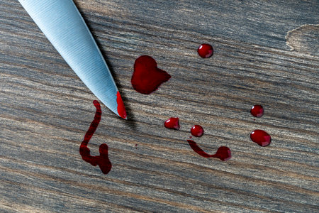 Kitchen knife with blood on the blade on the wooden table, close up, top viewの写真素材