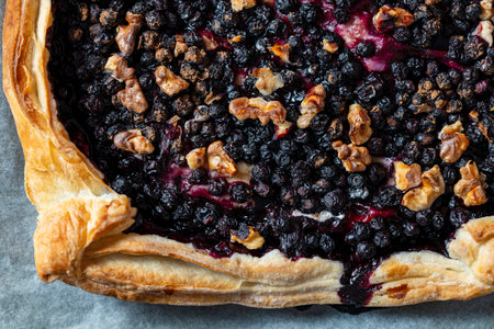 Puff pastry pie with blueberries and walnuts on a baking paper, close up, top viewの写真素材
