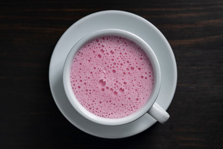 Pink matcha latte with milk in white cup on wooden background, close up, top view. Trendy drink conceptの写真素材