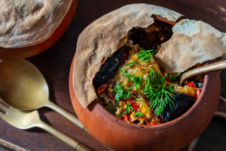 Clay pots with stewed vegetables on a wooden table, close up. Stewing food in earthenware is considered healthyの写真素材