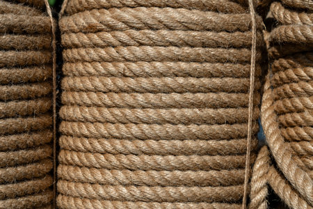 Natural jute hemp rope rolled into a coil, close up. Brown spool of linen rope texture on the...