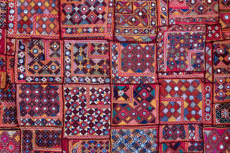 Detail old colorful patchwork carpet in background, India. Close up various textures of cloth sewn into one canvasの写真素材