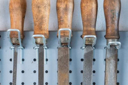 Old vintage rasps with wooden handles hanging on steel wall as background. A set of files and rasps...