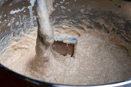 Kneading elastic dough for bread in a kneading machine in a bakery, close up. Mixer for kneading dough. Kneading yeast-free dough from whole grain and rye flourの写真素材