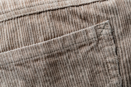 Texture backdrop of beige colored corduroy fabric cloth with pocket . Corduroy retro fabric background or texture. Close up viewの写真素材