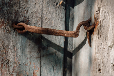Very rusty door hook closing a wooden door, close up. An old wooden gate locked with an equally old rusty hook. Vintage backgroundの写真素材