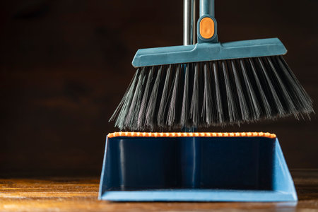 Cleaning plastic broom and dustpan on wooden floor indoors, close upの写真素材