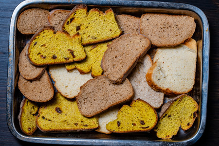 Various sliced fresh bread in a metal tray on the wooden table, close up. Arrangement with bakery productsの写真素材