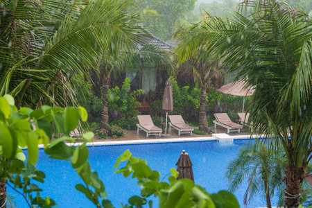 Tropical summer rain falling big rain drops falling down on swimming pool near sea on the beach in Phu Quoc island, Vietnam, Southeast Asia. Concept of nature and the environmentの写真素材