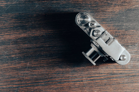 Old vintage retro photo camera on a wooden background, top view, copy space, close up. Obsolete nostalgia styleの写真素材