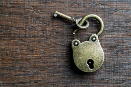 Vintage unlocked padlock and bronze key on a wooden background, close up, copy spaceの写真素材