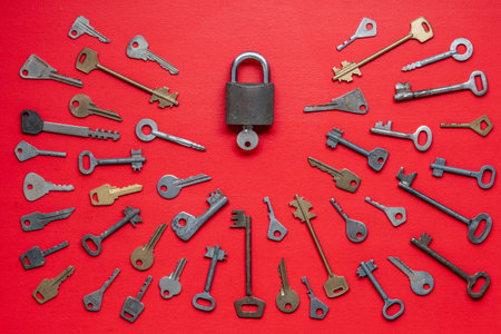 One lock and many different old keys on red background, top view, close up. Group of old keysの写真素材
