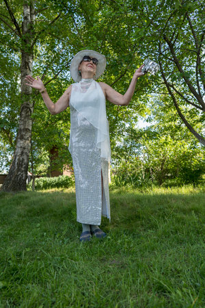 Portrait of a happy elderly woman 65 - 70 years old in a straw hat on the background of nature, close upの写真素材