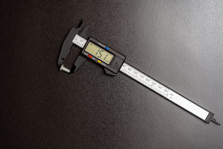Measuring the bolt length with an electronic digital caliper on a black background, close up, top view. Repair conceptの写真素材