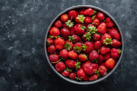 Fresh red strawberries in a metal bowl with water for washing after harvesting, close up, copy space, top view. Delicious, juicy red strawberries full of vitaminsの写真素材