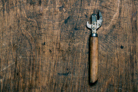 Old rusty bottle opener and canned food on a wooden background, top view, close up, copy space.の写真素材