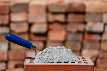 Dry cement or mortar. Cement powder and trowel on red brick at construction site, close upの写真素材