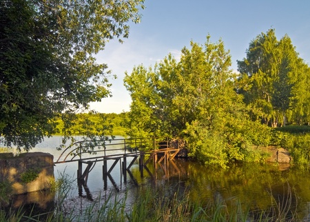 rusty old bridge across a small forest riverの写真素材