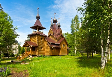 beautiful wooden church in the village against the backdrop of blue sky and green grassの写真素材